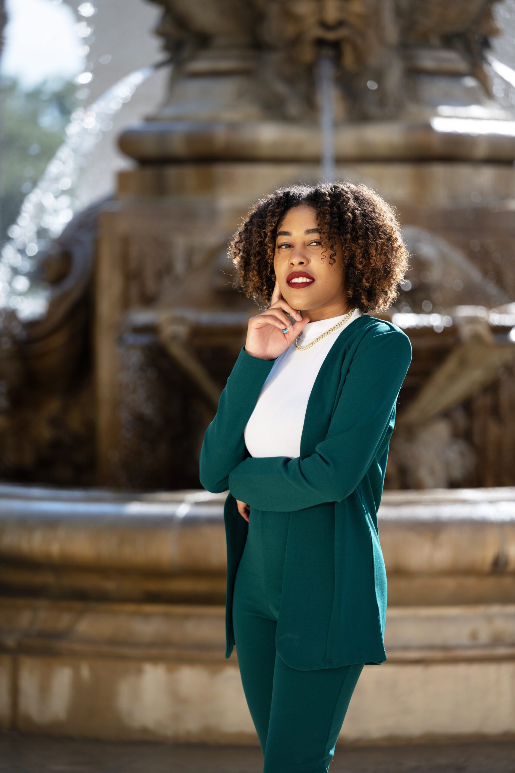 A Woman in a Green Suit Standing in Front of a Fountain